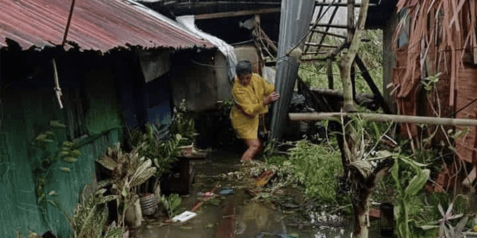 A woman navigates the destruction and flooding after Super Typhoon hits her community in the Phillipines
