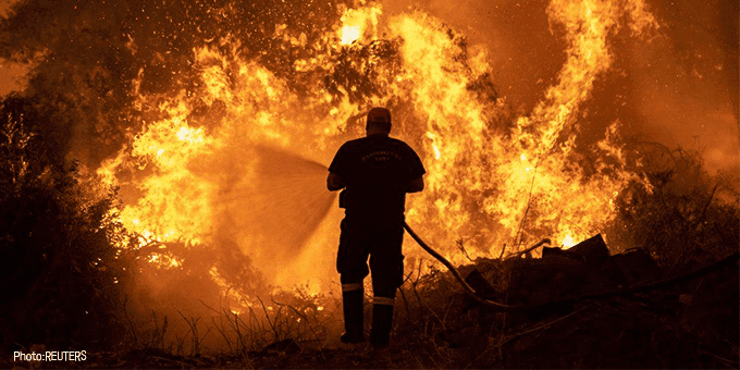 Firefighter hosing down large fire