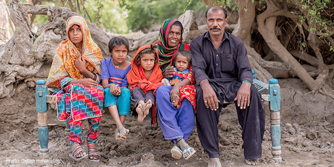 A family sit with their children against a backdrop of trees.