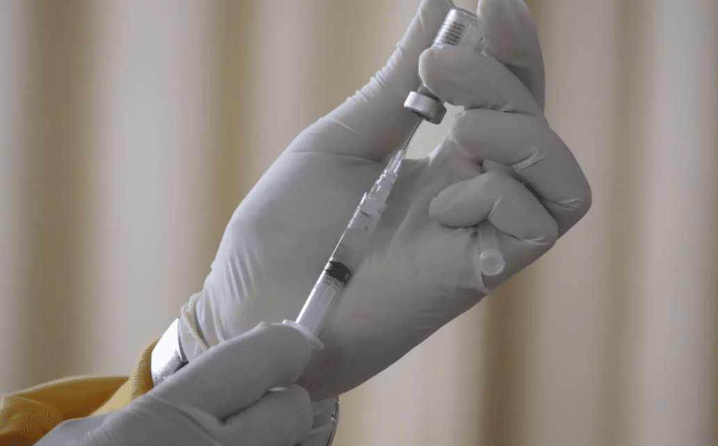 Person with white gloves holding a vaccination