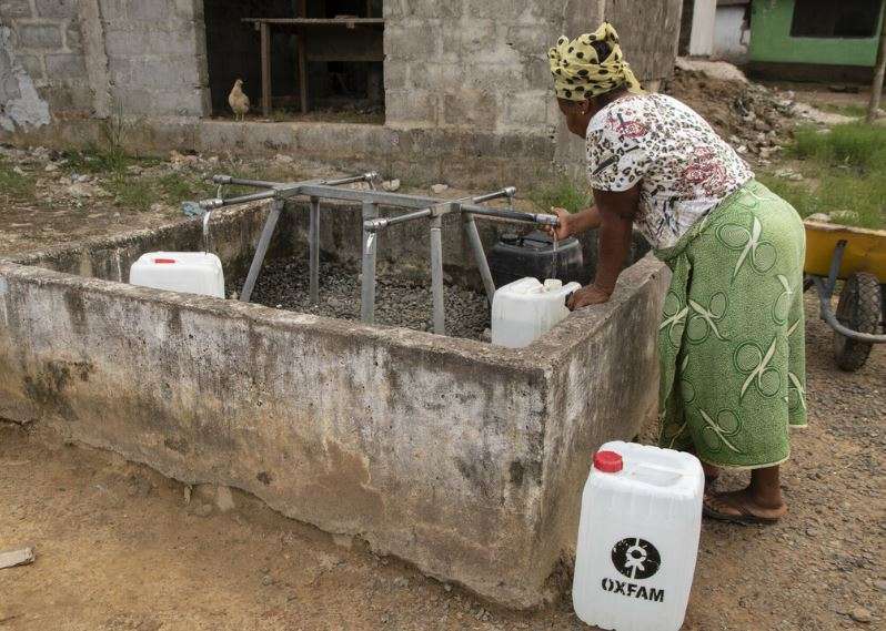 A lady bends over near a well