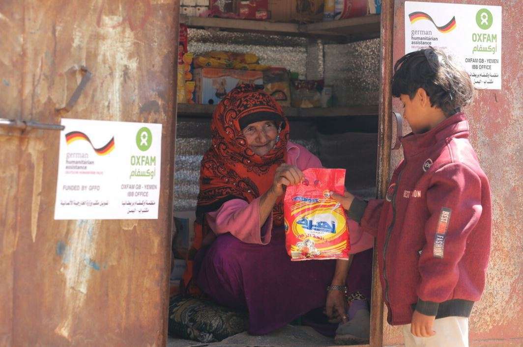 An older lady hands a young boy a parcel
