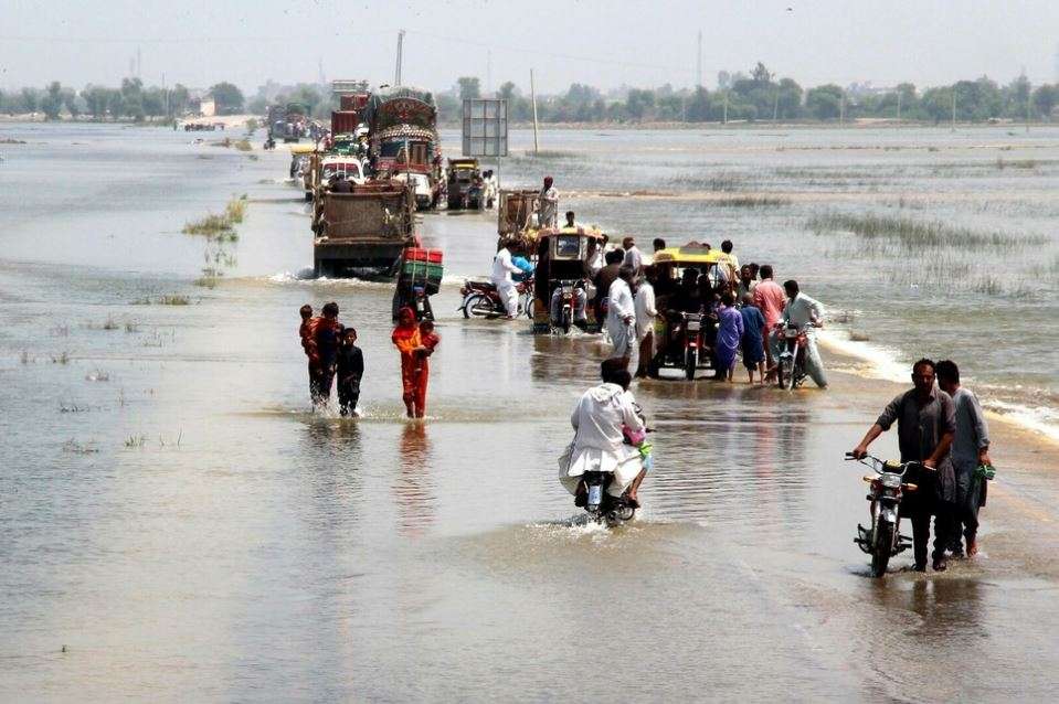 A group of people walk in a flooded area