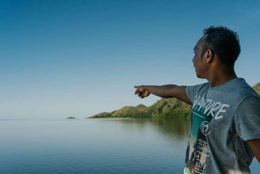 A man points at the ocean