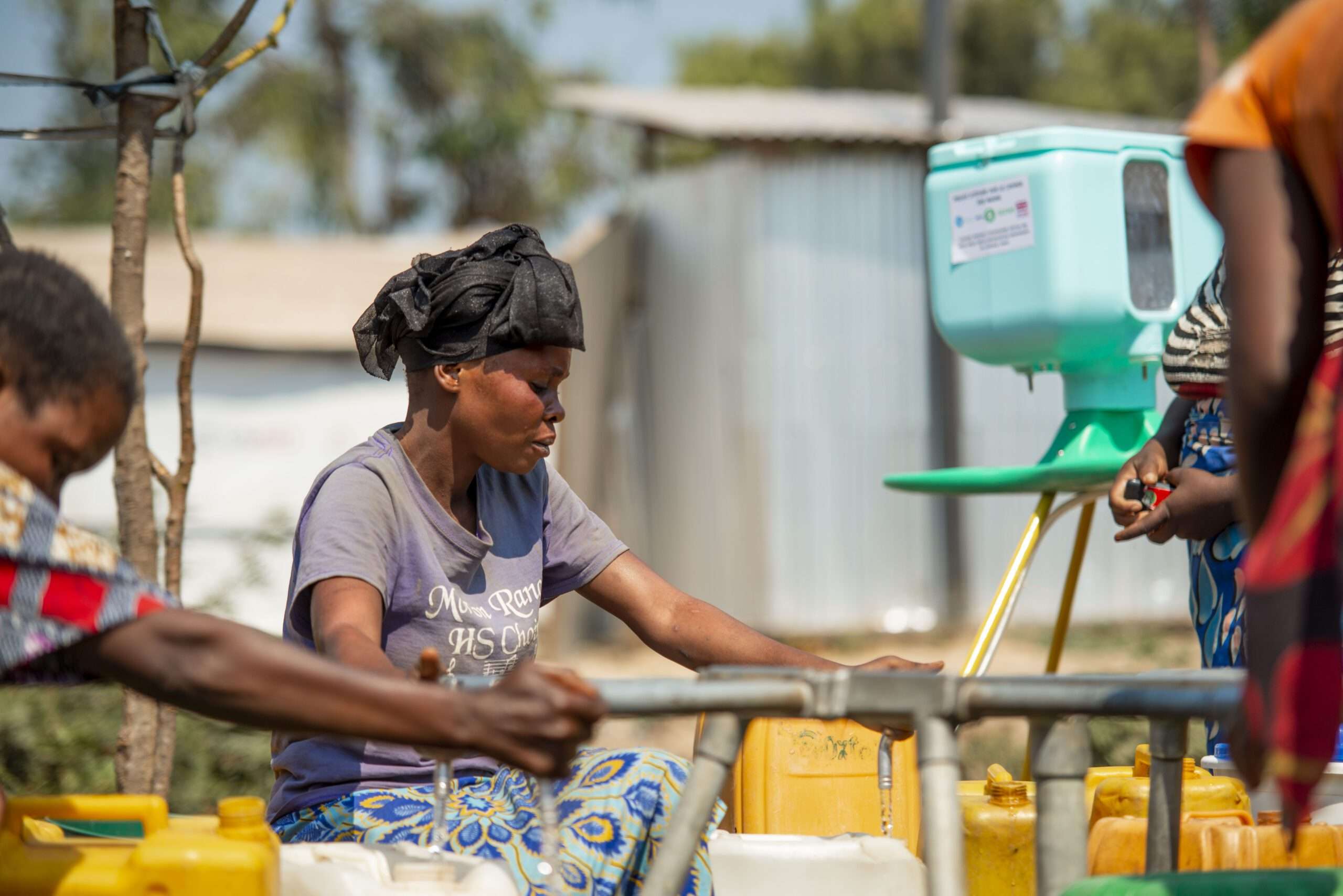 Nombe about to draw water from a tap supplied with water thanks to the photovoltaic system set up by Oxfam at the Kisalaba site.