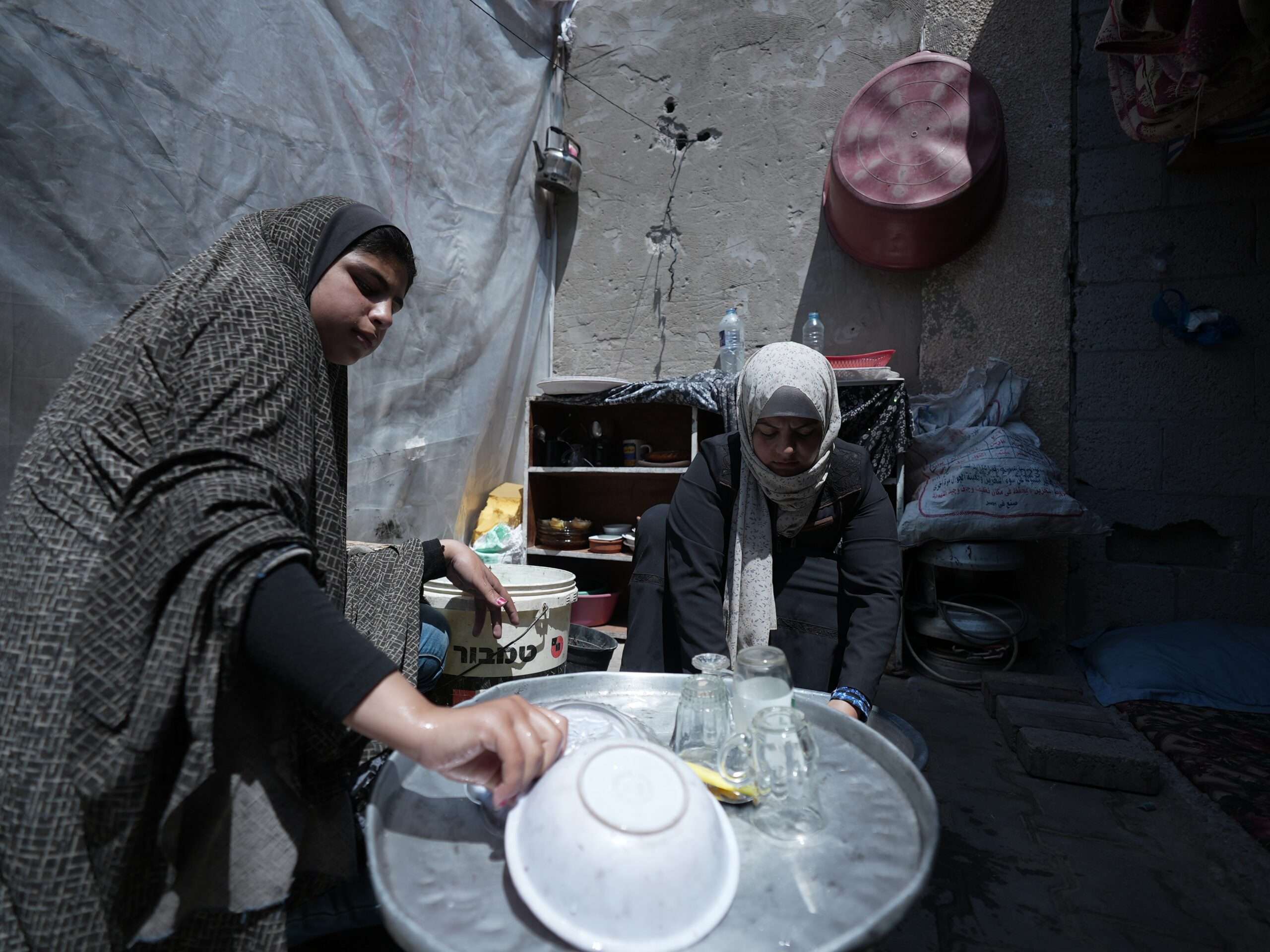 Ibrahim Al Batran's wife is washing dishes in a tent in the courtyard of al-Aqsa Hospital.