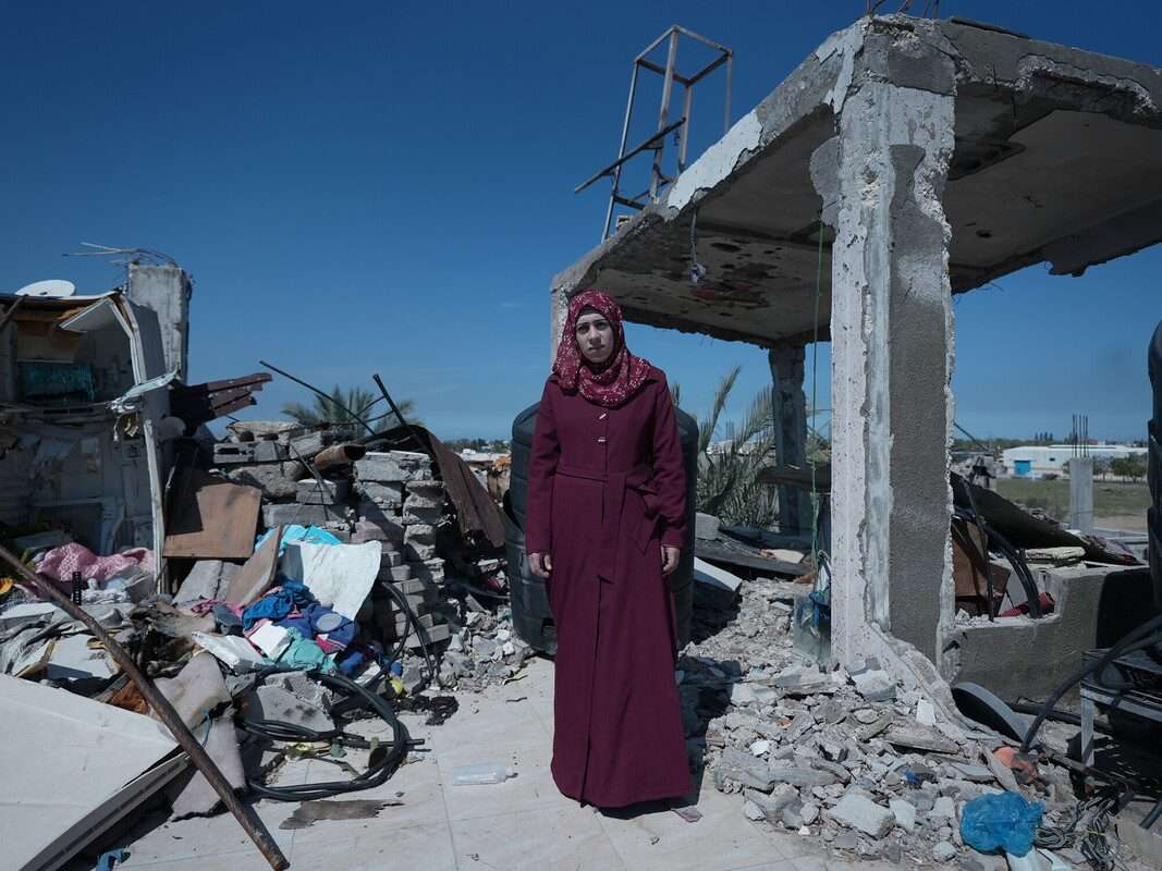 Palestinian woman stands in wreckage