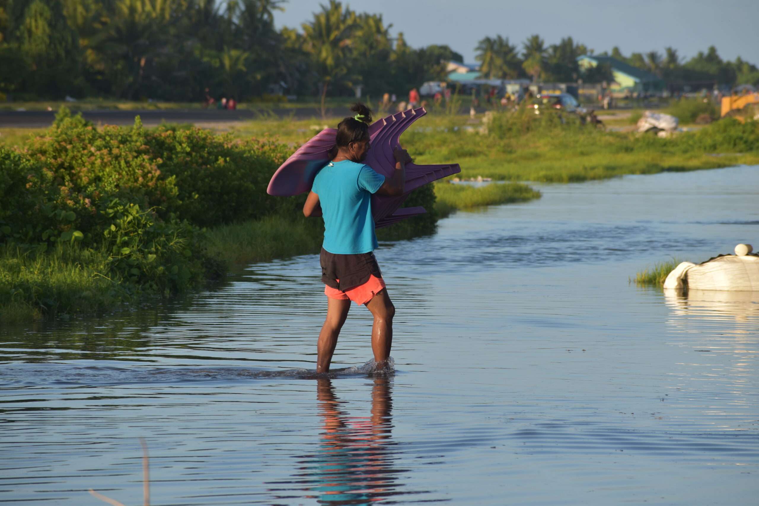 Woman carrying chairs through water from king tide