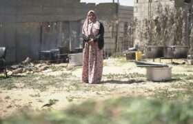 Ameera is standing next to the cooking pots she borrowed from friends and neighbours to cook food and sell it.