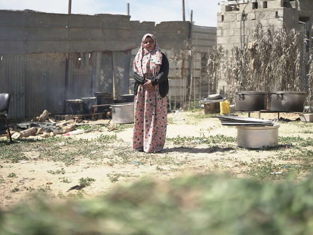 Ameera is standing next to the cooking pots she borrowed from friends and neighbours to cook food and sell it.