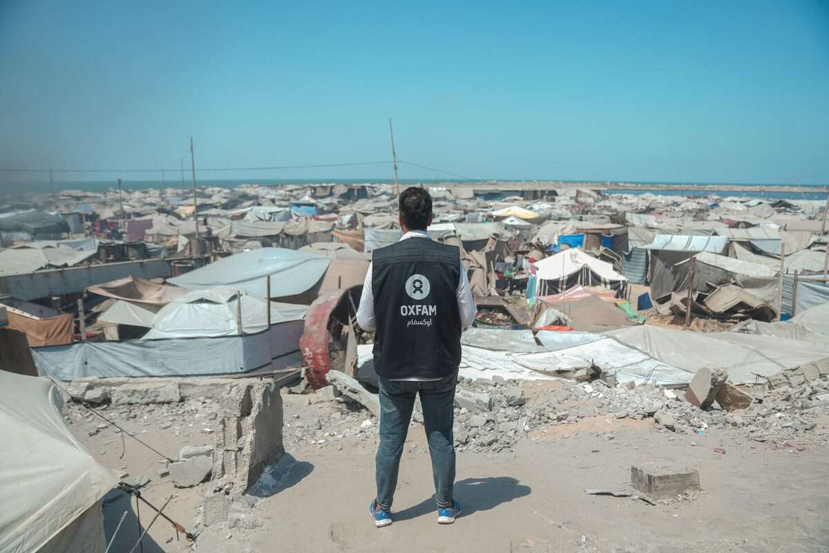 Osama, Oxfam Staff, walks among tents and rubble in Gaza City