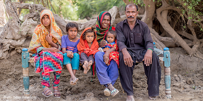 A family sit with their children against a backdrop of trees.