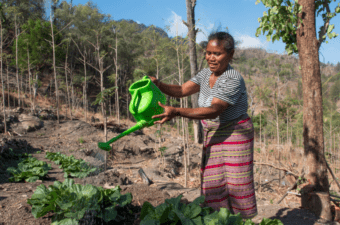 A woman holds a green watering can