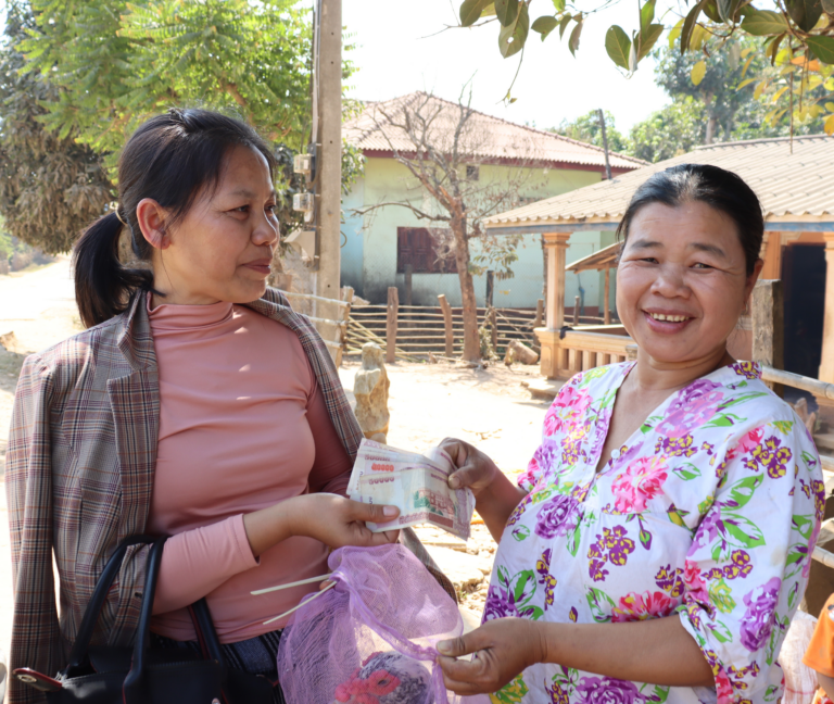 Woman giving customer cash in Laos