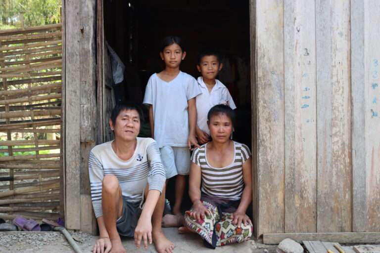Family posing in front of their home in Laos