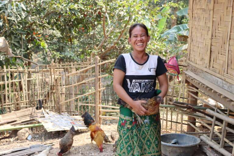 Woman holding a hen at her chicken farm in Laos