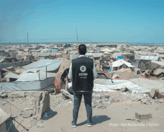 Osama, Oxfam Staff, walks among tents and rubble in Gaza City