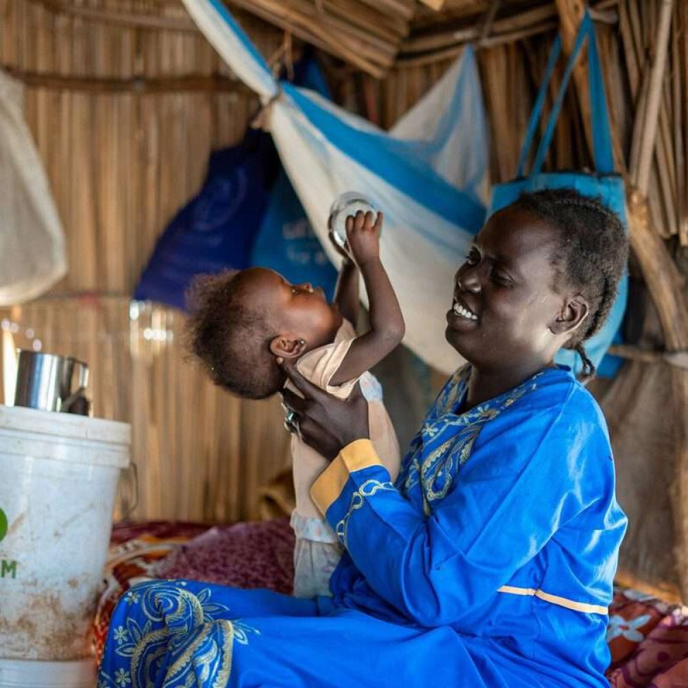 33-year-old Ayul Ajak, a visually impaired mother of six plays with her child at her home in her makeshift home in Renk, South Sudan after she fled her home in Sudan